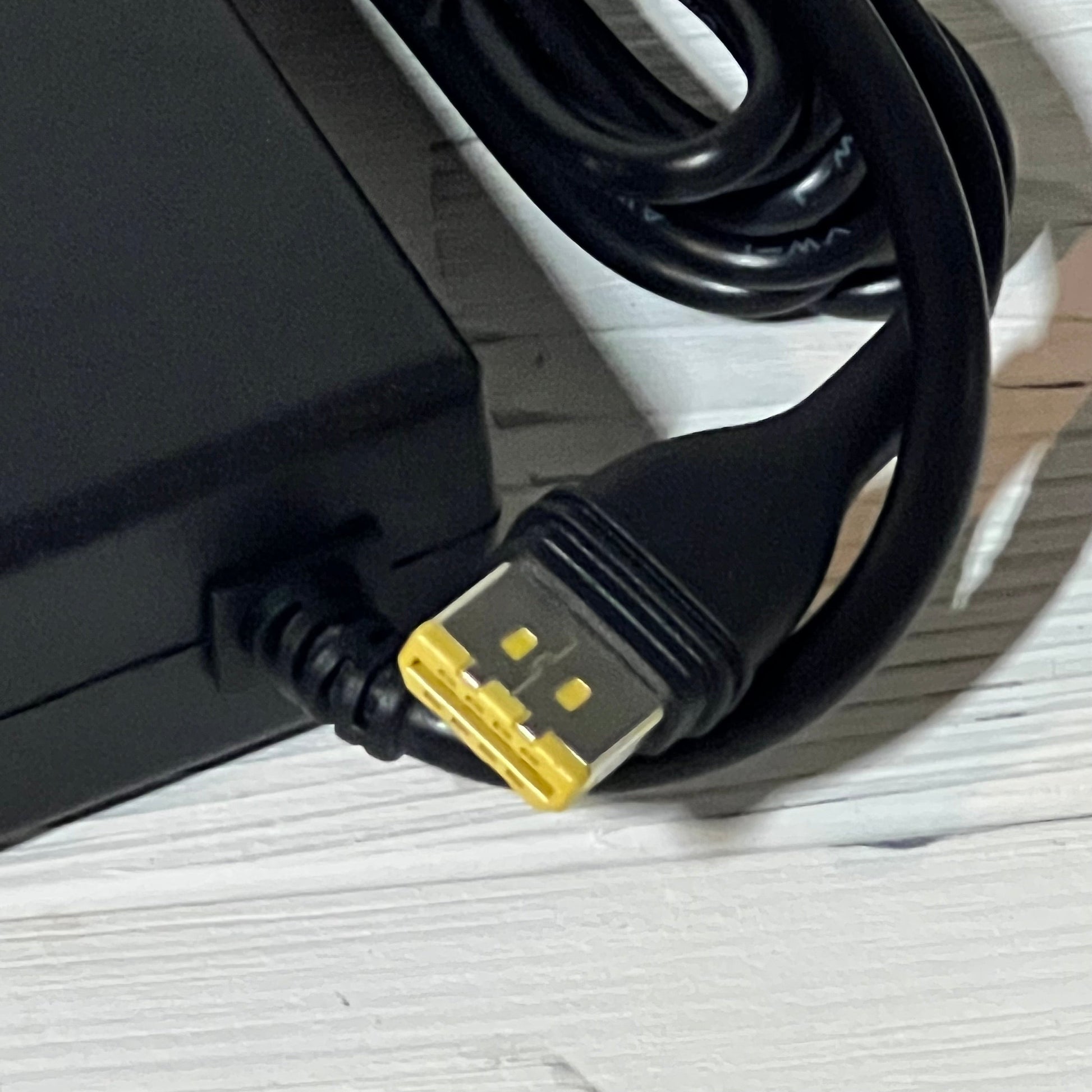 Black 12V adapter cable with yellow connector for Resmed AirSense 11 CPAP, shown on a light wooden surface.