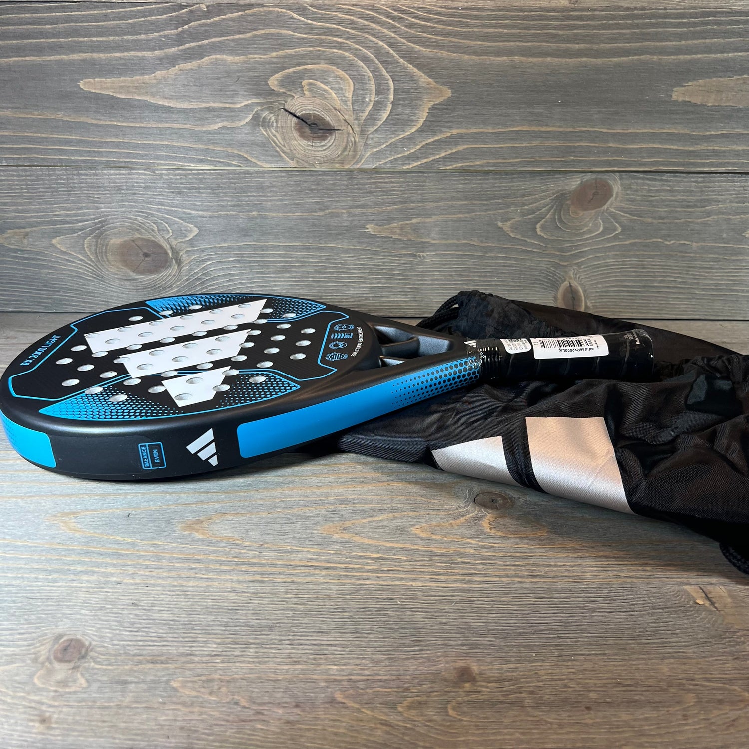 Blue Adidas Rx 2000 Light padel racket with sleek design, placed on a wooden surface, ideal for enhancing your game.