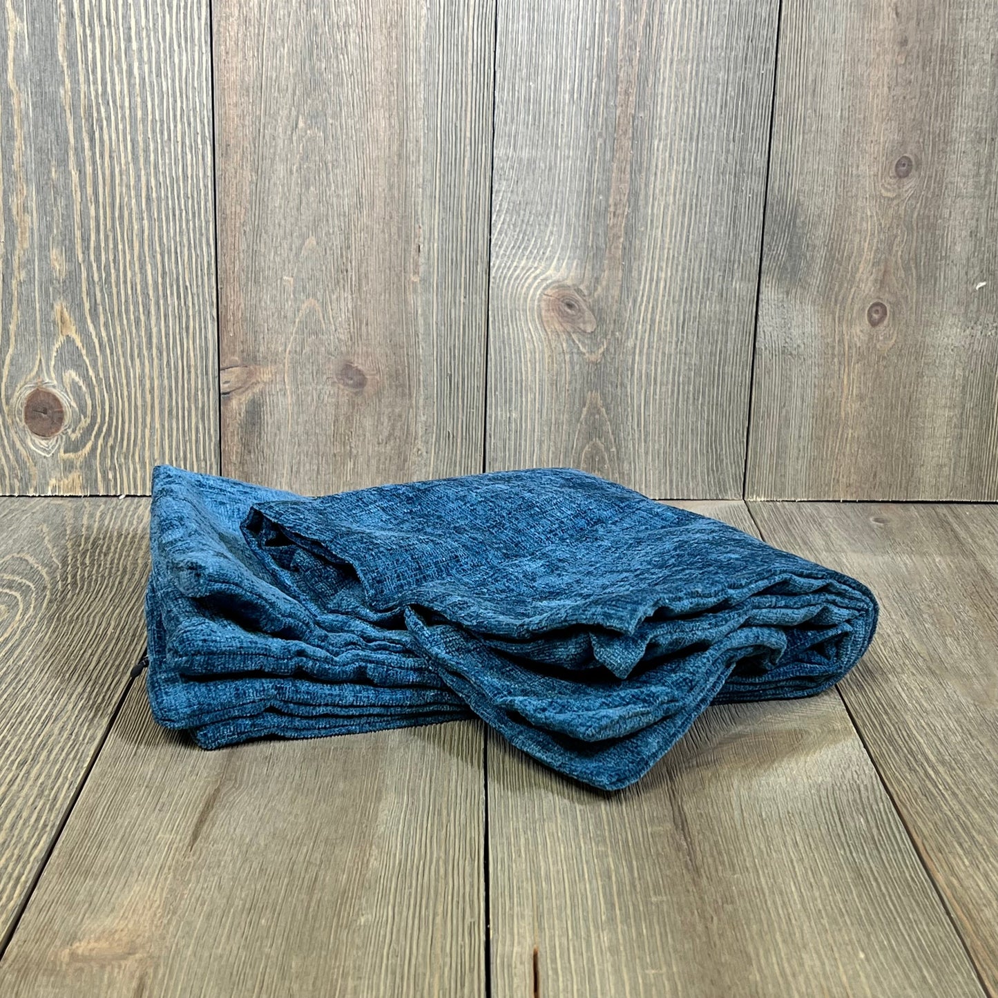 Soft chenille blue pillow covers folded on wooden background, perfect for enhancing a sofa or living room decor.