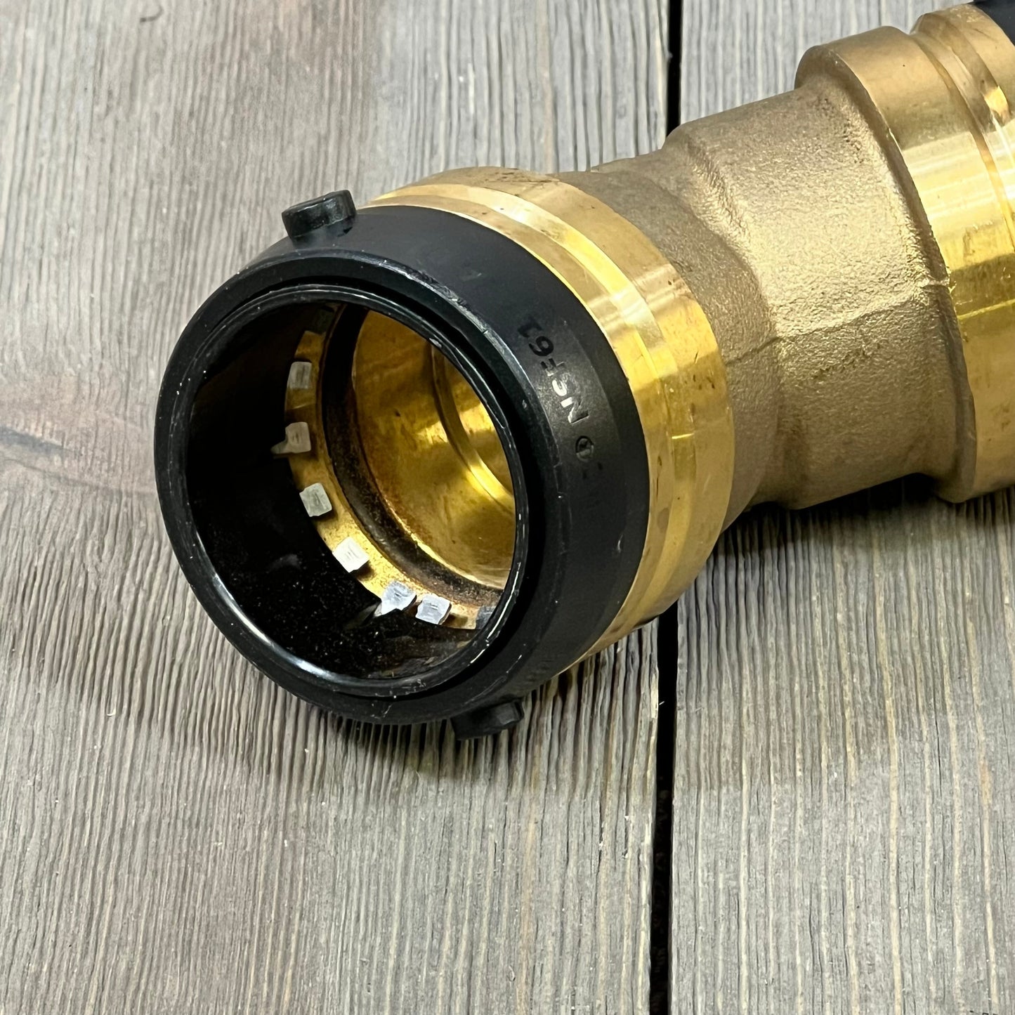 SharkBite 1-1/2 Inch 45 Degree Elbow fitting, brass push-to-connect for PEX, copper, CPVC pipes on wood surface.