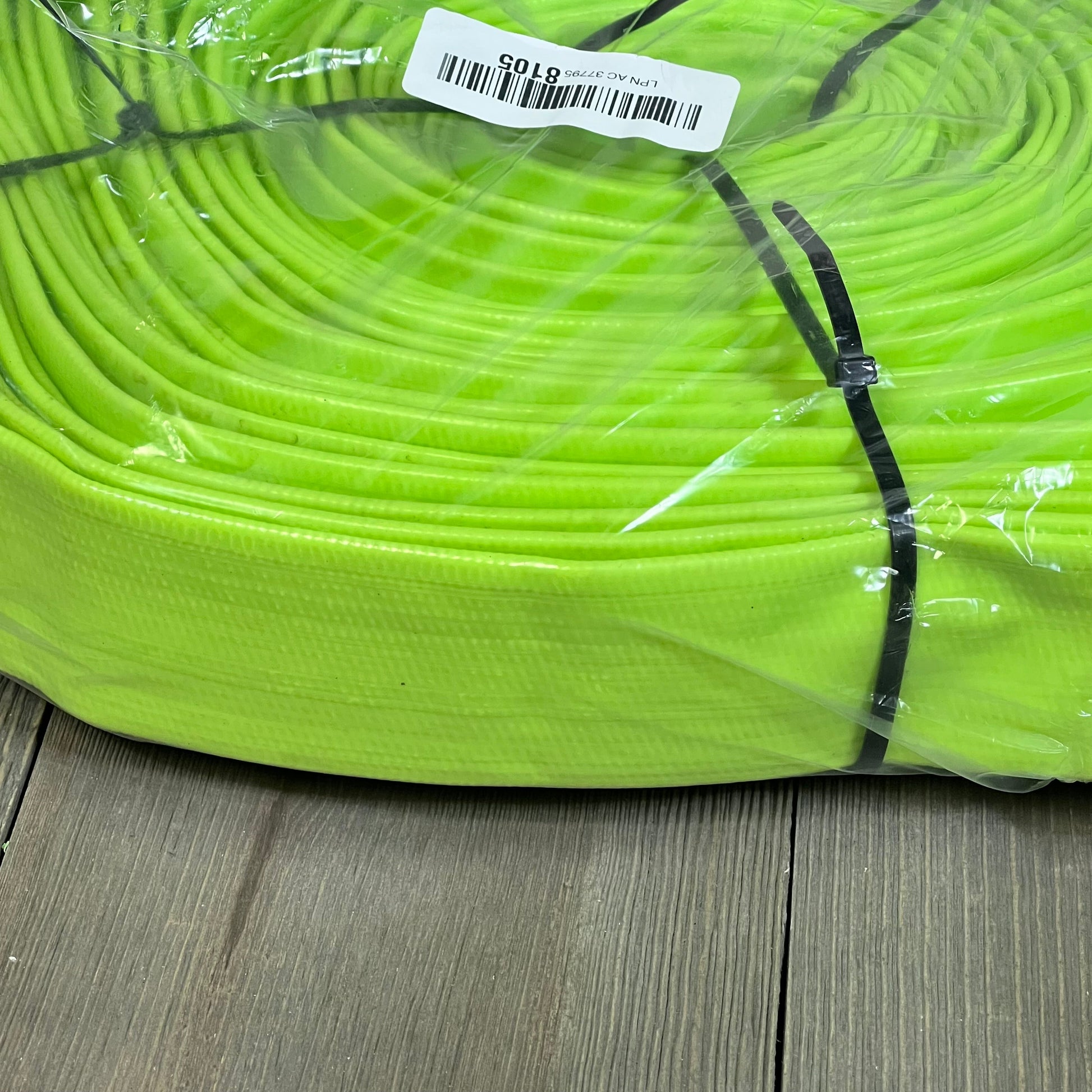Heavy-duty green pool backwash hose, 1-1/4'' x 100 ft, coiled and secured with clamps for easy drainage.