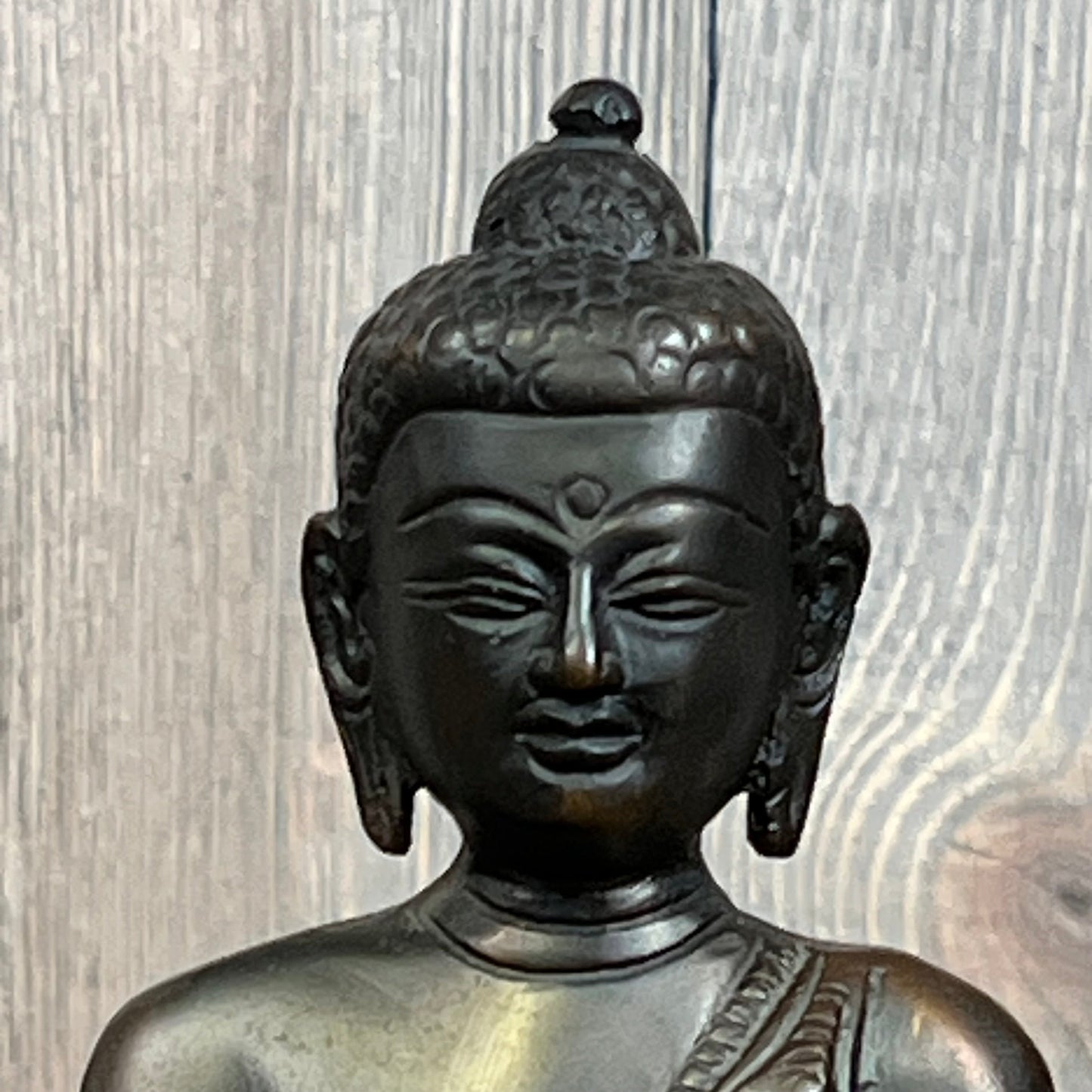 Gautama Buddha statue with serene expression, detailed craftsmanship, set against wooden background. Perfect for meditation spaces.