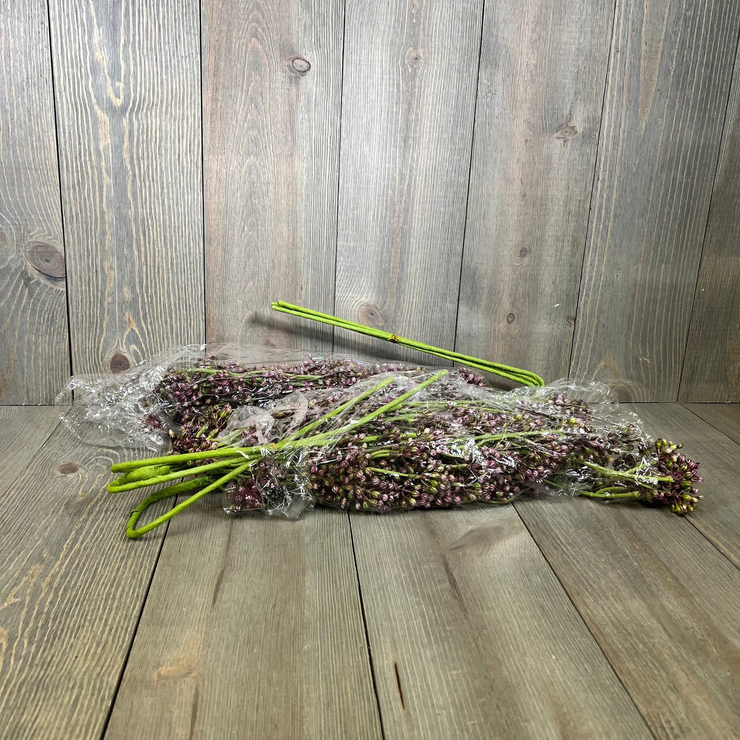 Faux plum sedum berry stems wrapped in plastic on a wooden surface, perfect for autumn and Thanksgiving décor.
