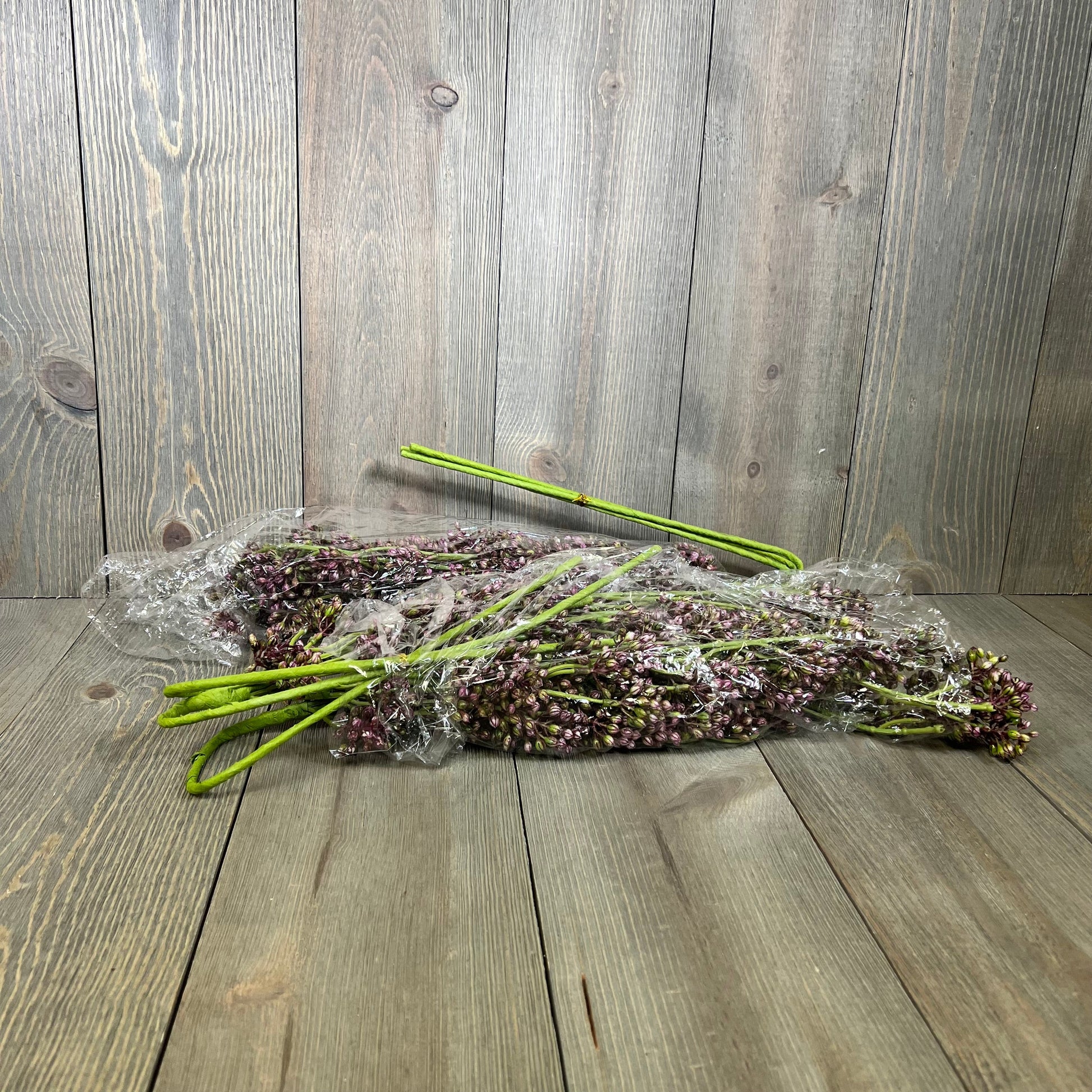 Faux plum sedum berry stems wrapped in plastic on a wooden surface, perfect for autumn and Thanksgiving décor.