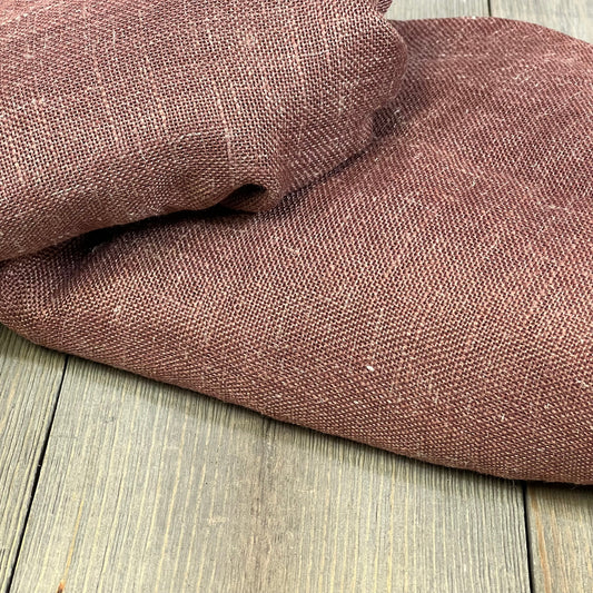 Chocolate brown linen curtains folded, showcasing thick textured fabric for bedroom or living room decor.