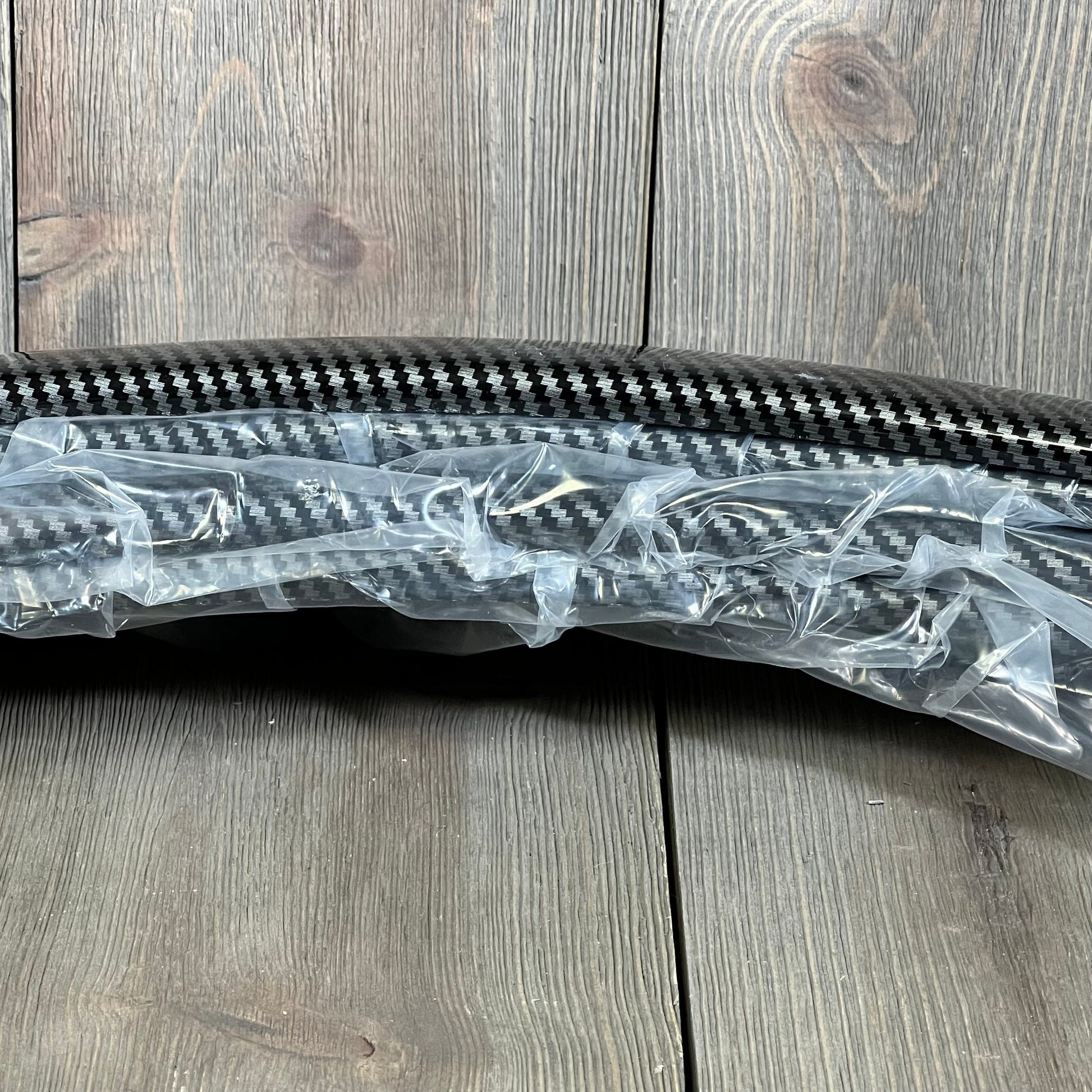 Carbon fiber DREAMIZER 2" car fender flares wrapped in protective plastic, ready for installation on vehicle wheel arches.