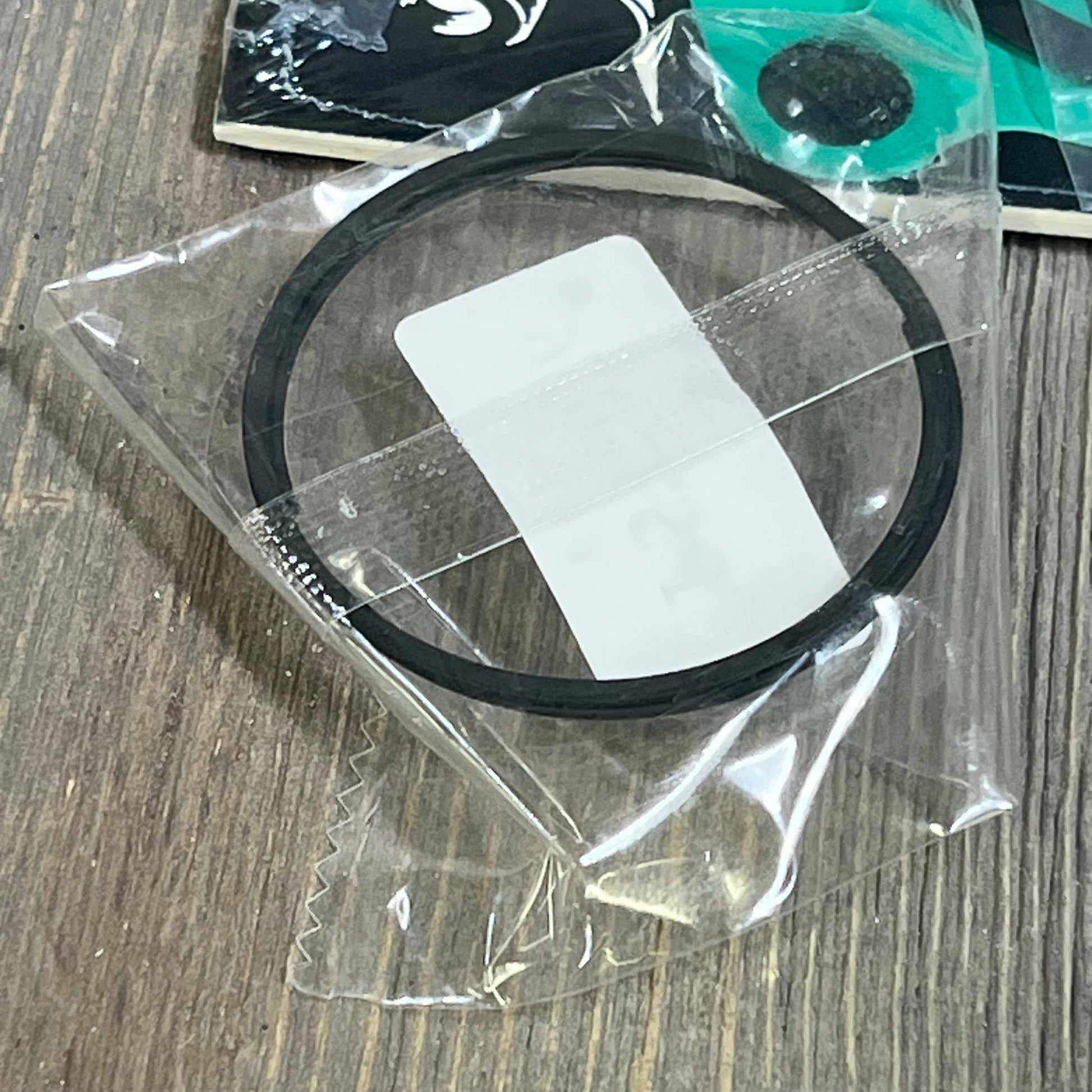 Piston ring for Kawasaki KX85 2001-2013, shown in protective packaging on a wooden surface.