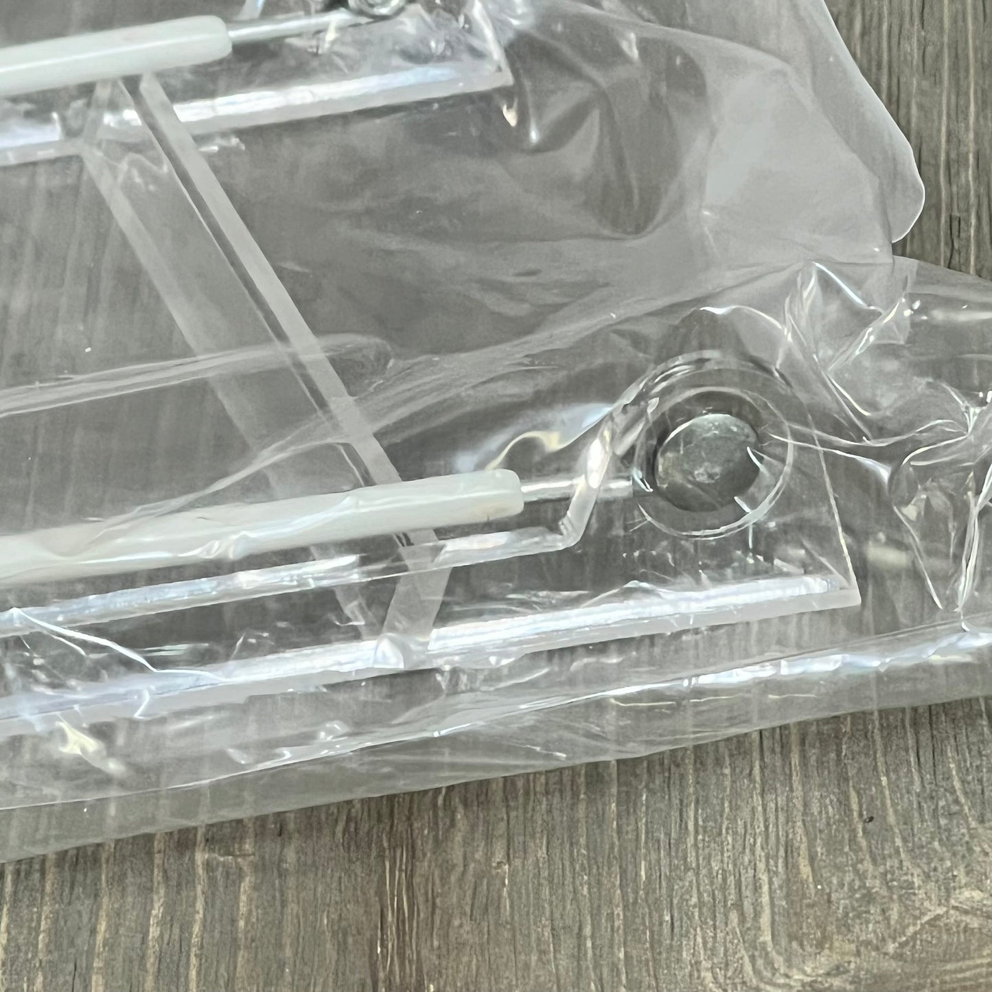 Clear acrylic plate stand wrapped in protective plastic, showcasing a sturdy build for displaying plates and books.