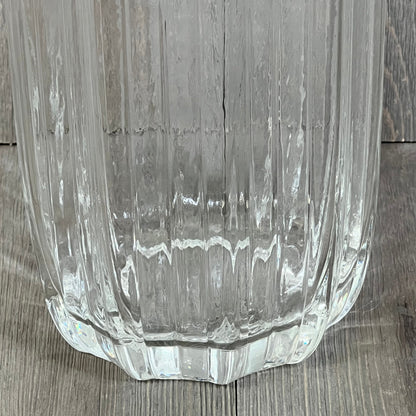 Tall clear glass vase with a simple striped design, perfect for home decor and flower arrangements, stands elegantly on a wooden floor.