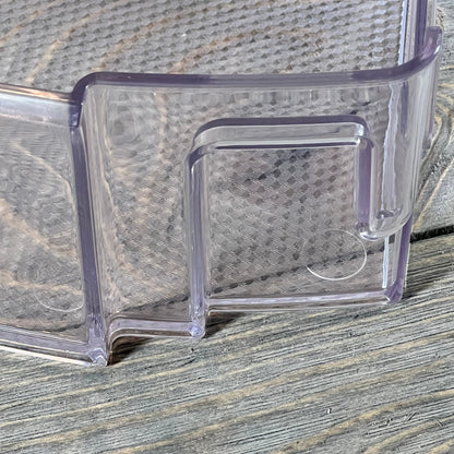 Clear plastic refrigerator door shelf bin MAN63948502 for LG and Kenmore, close-up view on wooden surface.