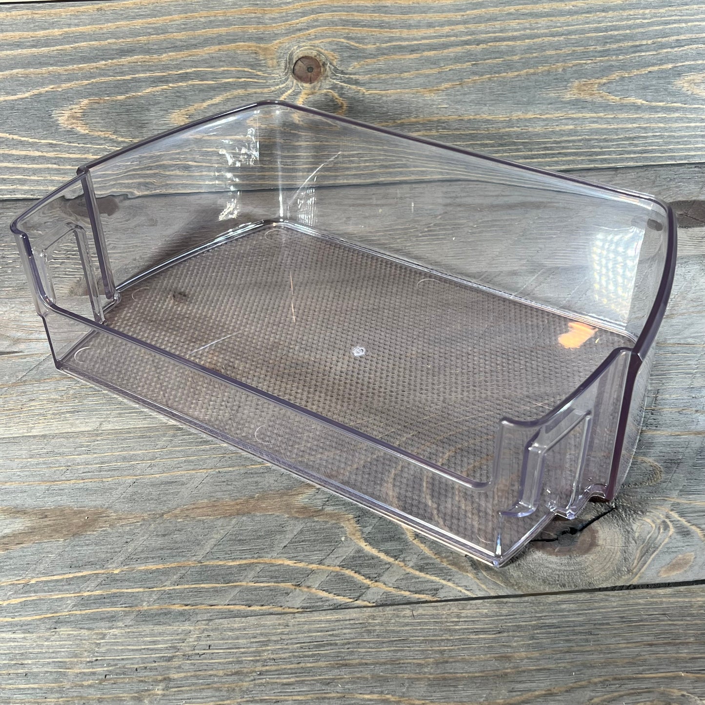 Clear replacement refrigerator door shelf bin for LG and Kenmore, part MAN63948502, on wooden surface.