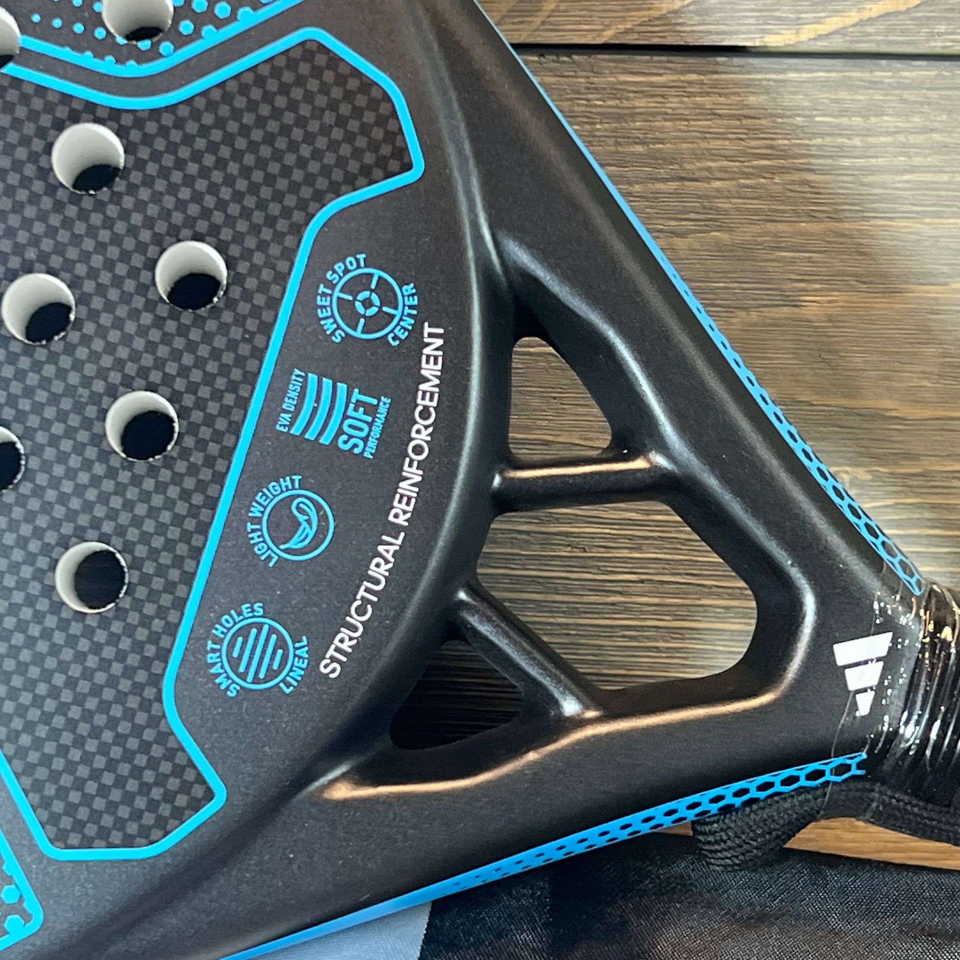 Close-up of 1057266554-Adidas Rx 2000 Light padel racket, showcasing blue detailing and structural reinforcement.