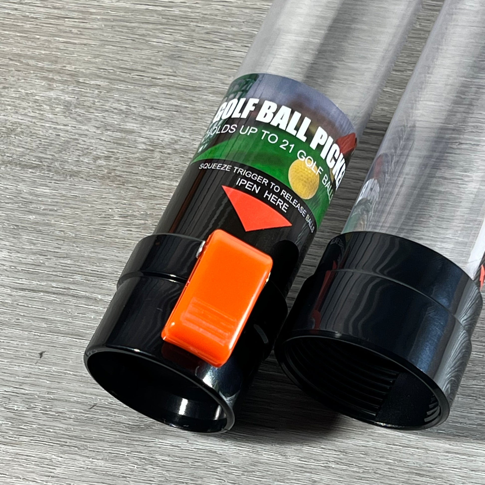 Close-up of a golf ball retriever tool with a 36-inch plastic tube, showing the orange release trigger.