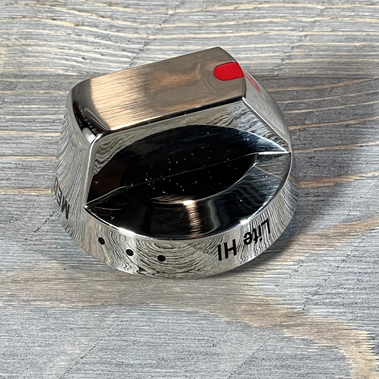 Close-up of a shiny Samsung gas stove burner control knob with a brushed metal finish and red indicator.