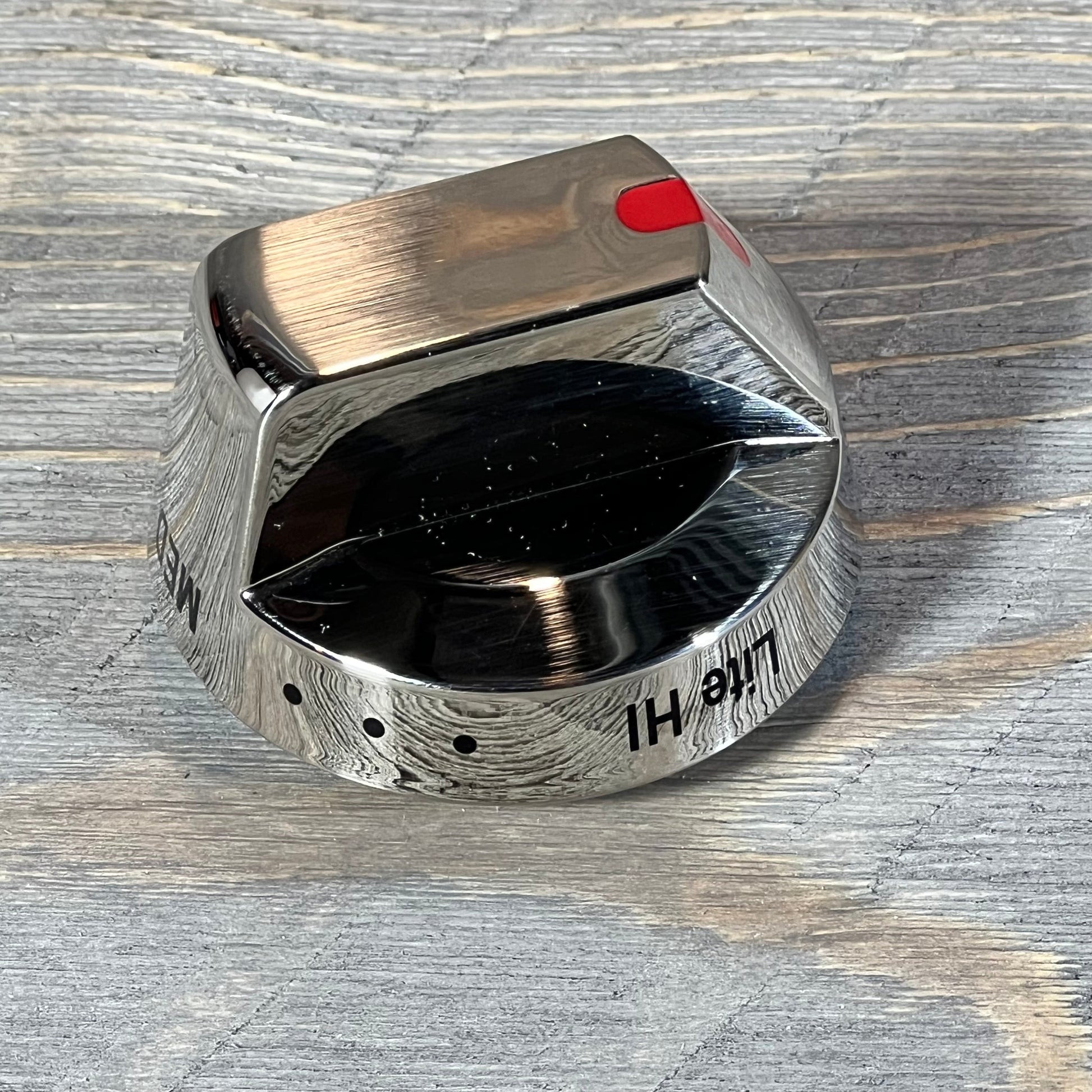 Close-up of a shiny Samsung gas stove burner control knob with a brushed metal finish and red indicator.