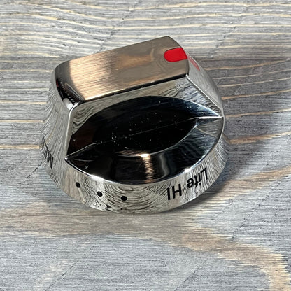 Close-up of a shiny Samsung gas stove burner control knob with a brushed metal finish and red indicator.
