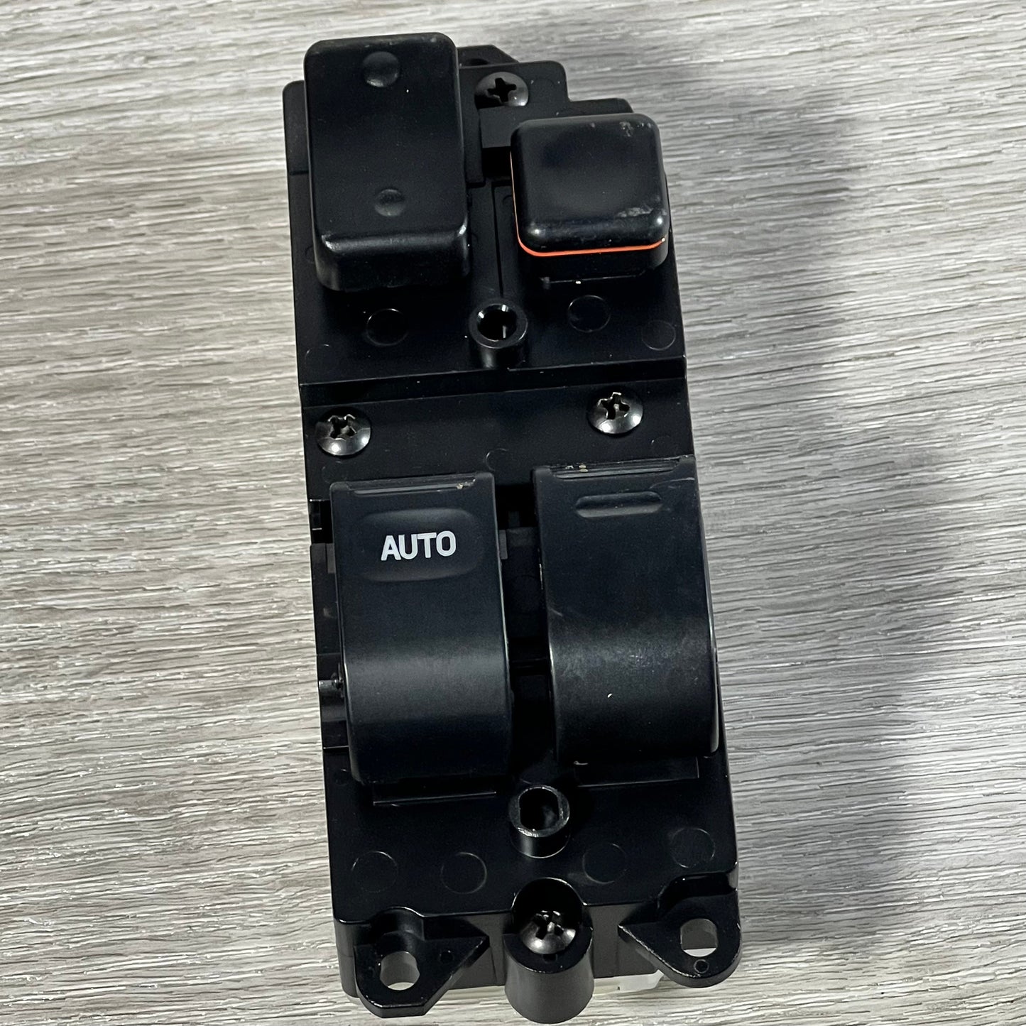 Close-up of Dorman 901-711 window switch featuring auto button for Toyota models, placed on a wooden surface.