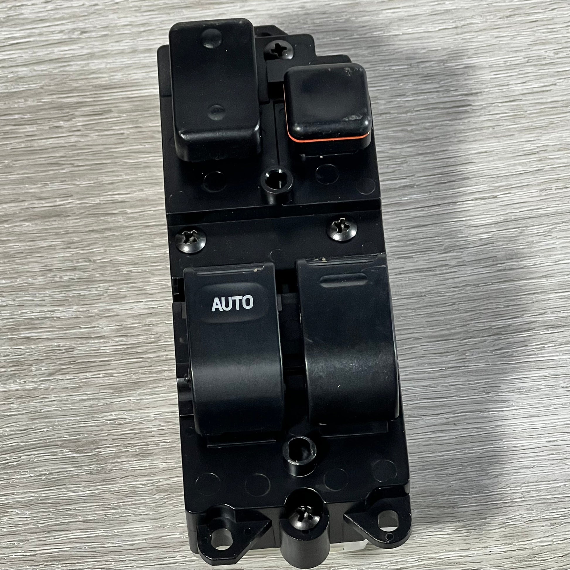 Close-up of Dorman 901-711 window switch featuring auto button for Toyota models, placed on a wooden surface.