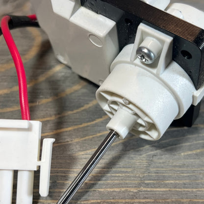 Close-up of FDQC18EL4F evaporator fan motor with wiring for Frigidaire and Kenmore refrigerators on wooden surface.