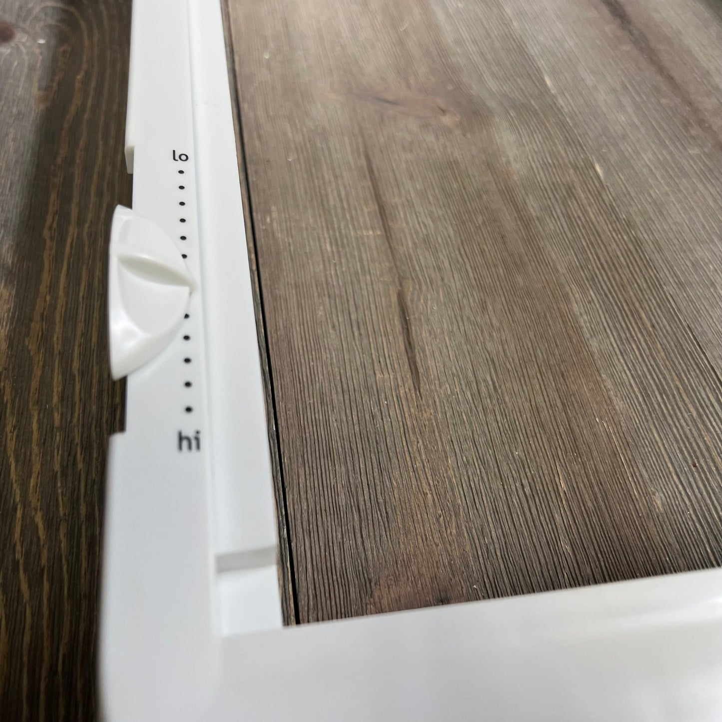 Close-up of the adjustable slider on the upgraded refrigerator crisper drawer cover frame, compatible with Frigidaire.