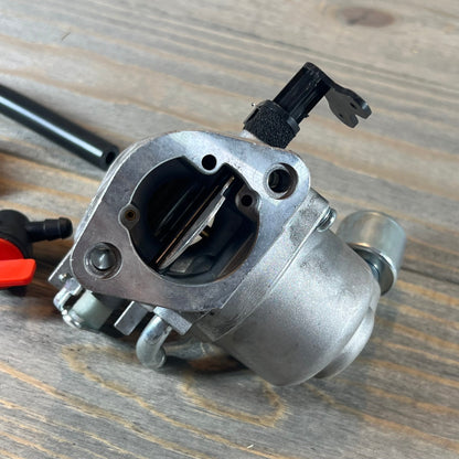 Close-up of the CARBBIA 594207 carburetor, compatible with 40N777 and 40N877 Intek engines, on a wood surface.