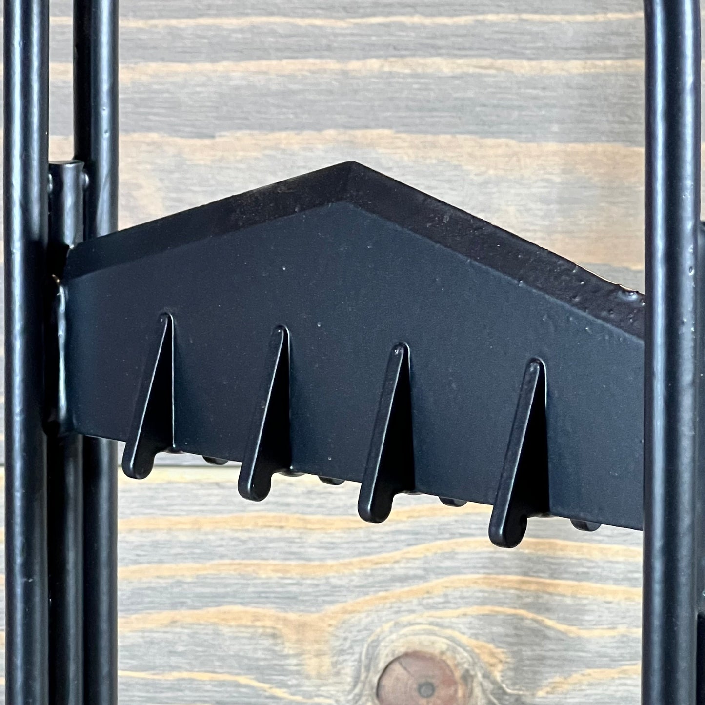 Close-up of the sharp, serrated edge of a manual log splitter wedge against a wooden background.