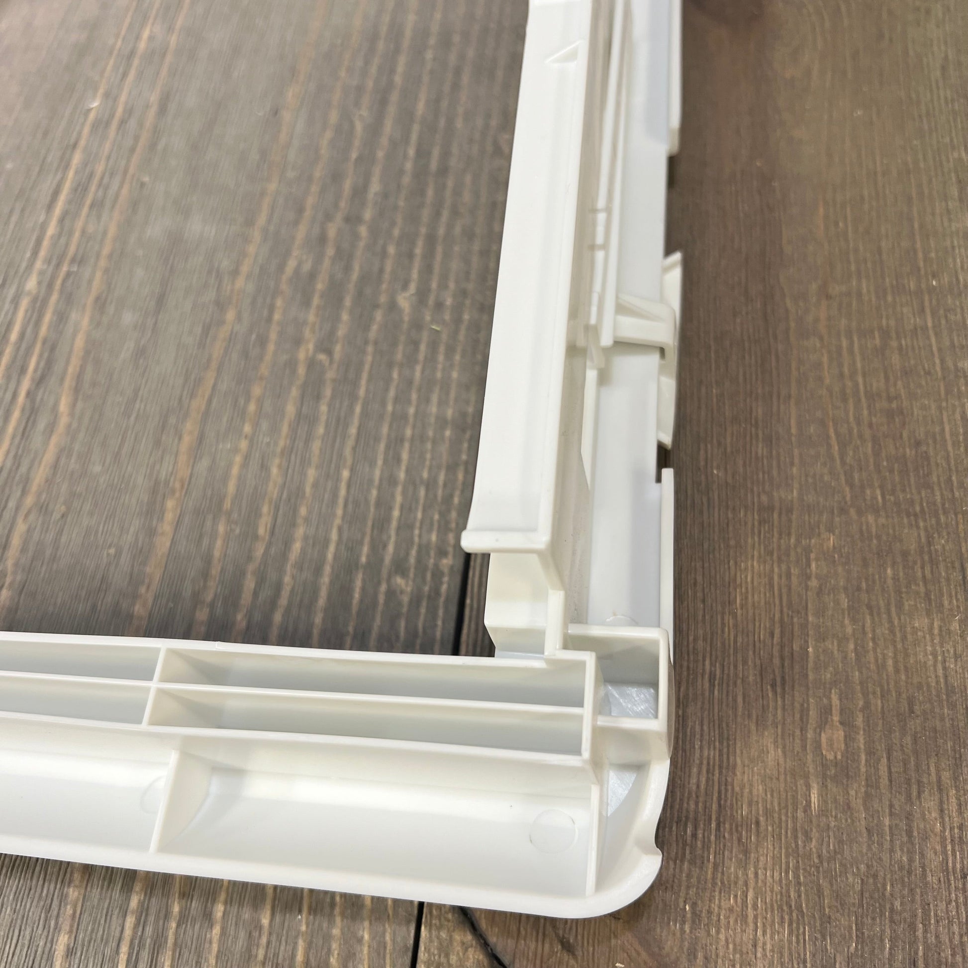Close-up of upgraded refrigerator crisper drawer cover frame, highlighting corner details and compatibility with Frigidaire models.
