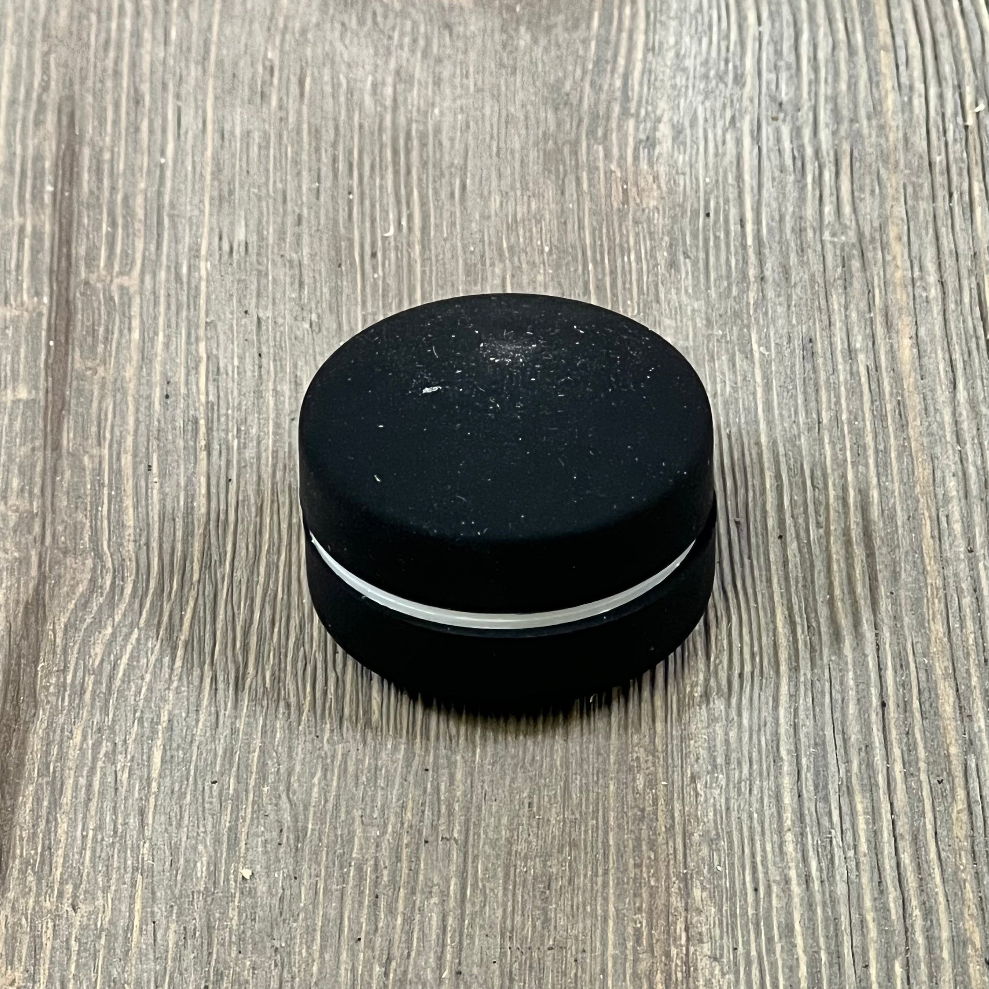 Black magnetic silicone curtain weight on wooden surface, ideal for securing bathroom curtains and outdoor use.
