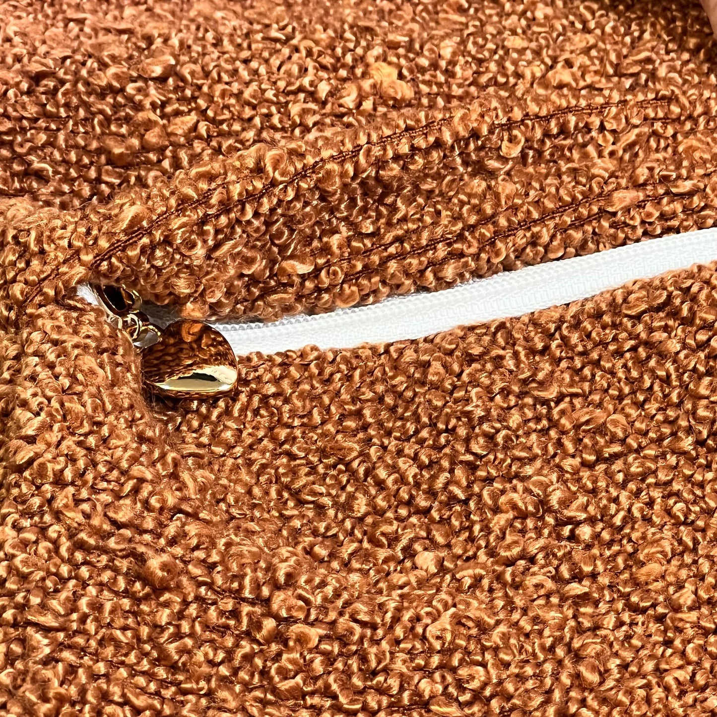 Close-up of rust-colored boucle textured throw pillow cover with zipper, adding cozy style to modern home decor.