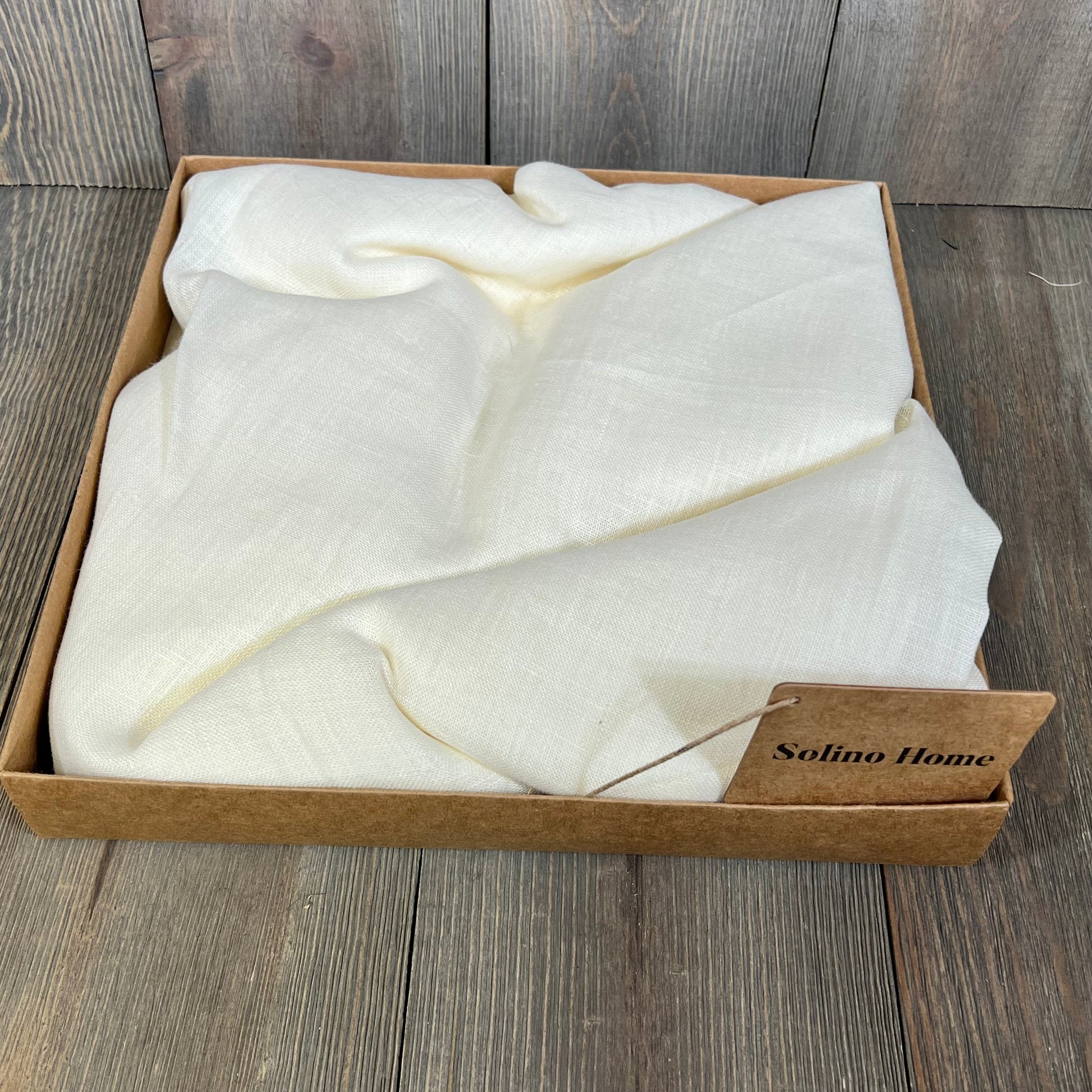 Ivory linen sheer curtain neatly folded in a box, showcasing its light-filtering fabric and elegant texture.