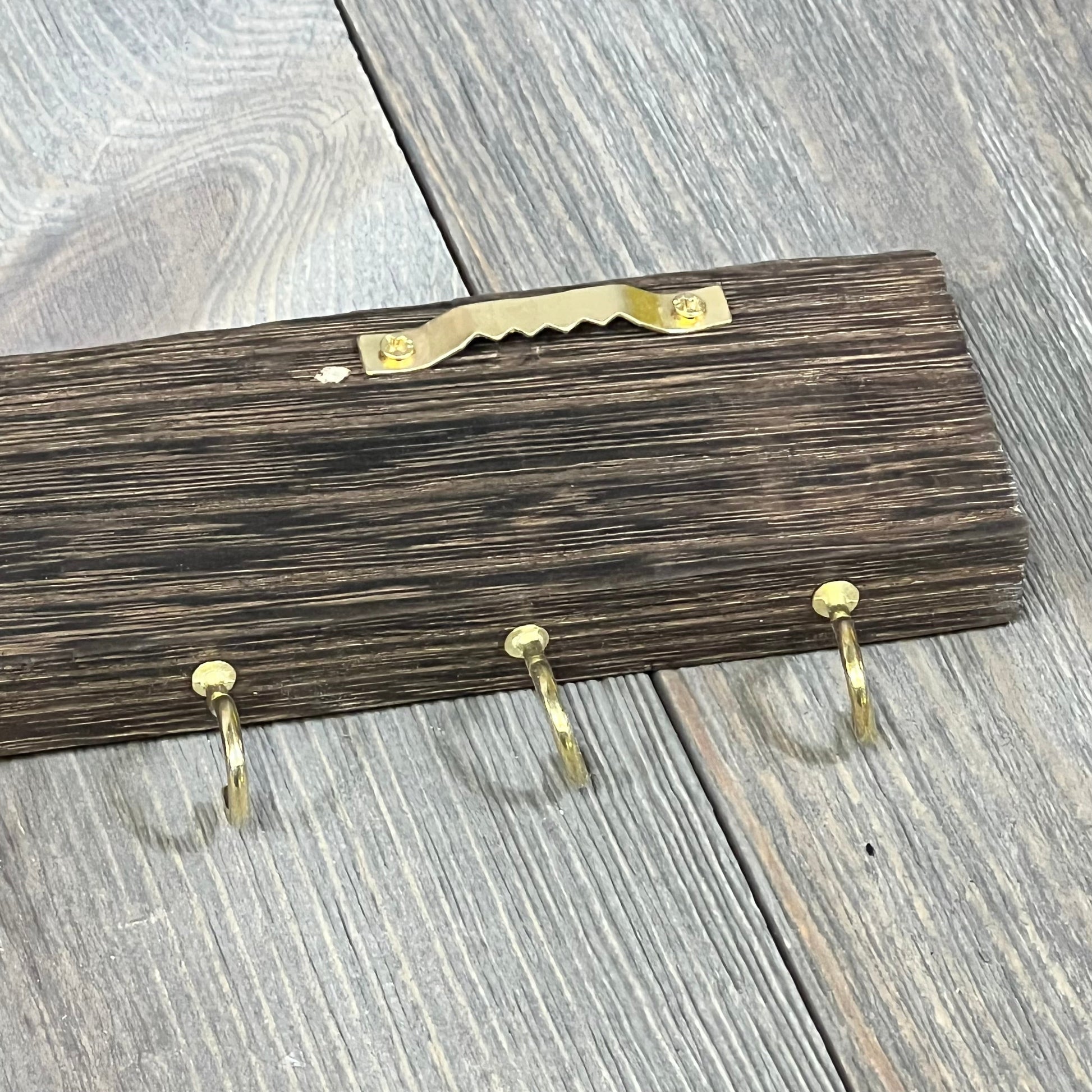 Rustic wooden barn door jewelry organizer with gold hooks for necklaces and bracelets, wall-mounted storage solution.