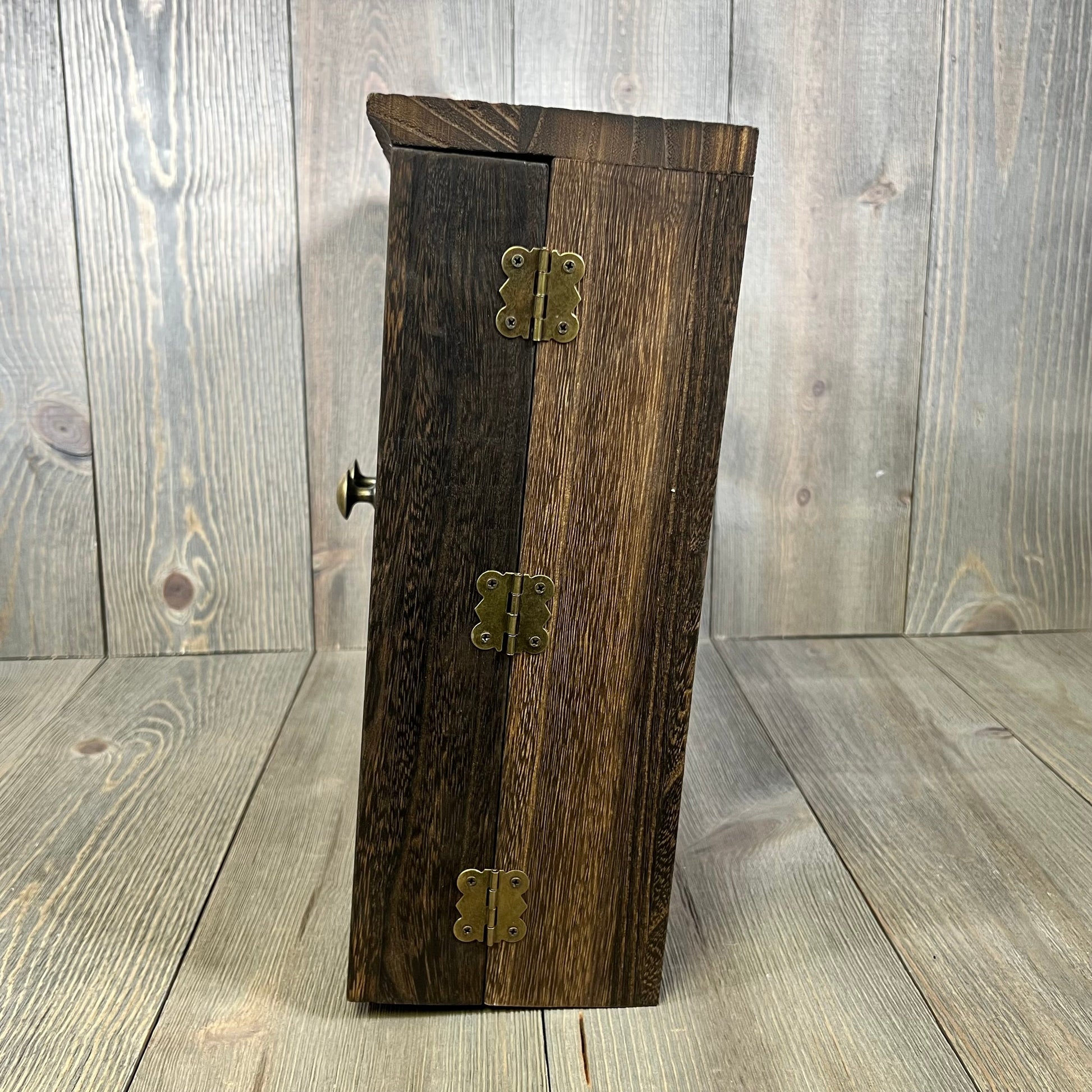 Rustic wooden barn door jewelry organizer with brass hinges, perfect for wall-mounted necklace and earring storage.