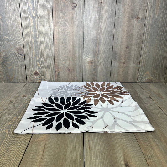 Geometric black and brown floral outdoor pillow cover on wooden surface, perfect for enhancing patio decor with elegance.