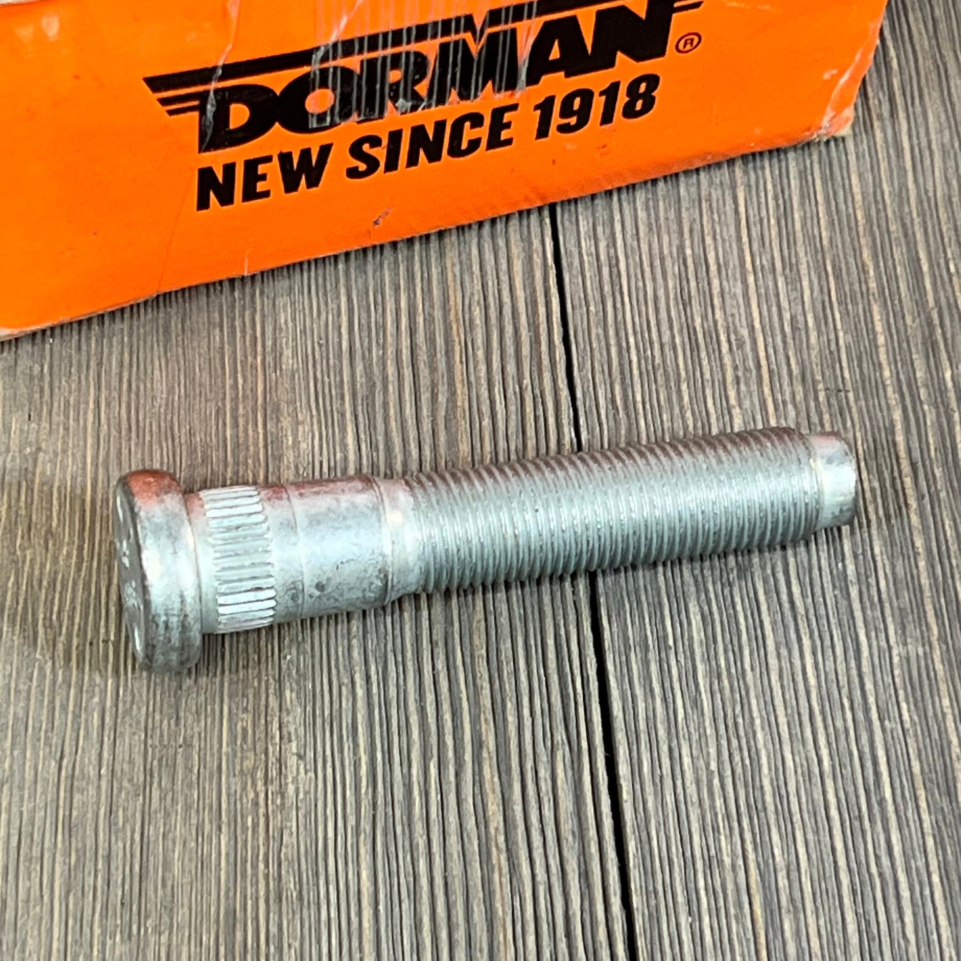 Dorman 610-383 serrated wheel stud with .643 in. knurl and 3-5/32 in. length for Dodge cars, shown on wooden surface.