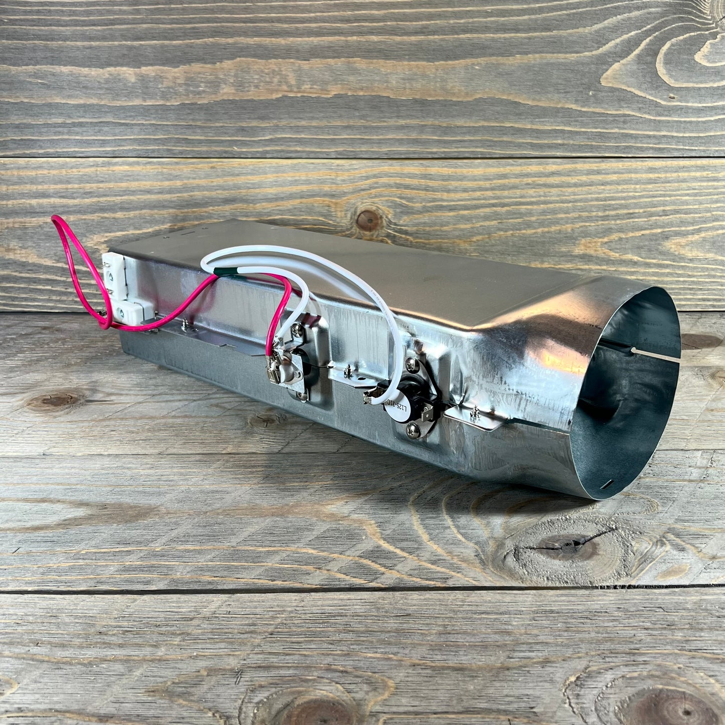 Dryer heating element 5301EL1001H for LG TROMM, showcasing three-prong thermostat and wiring on wooden surface.