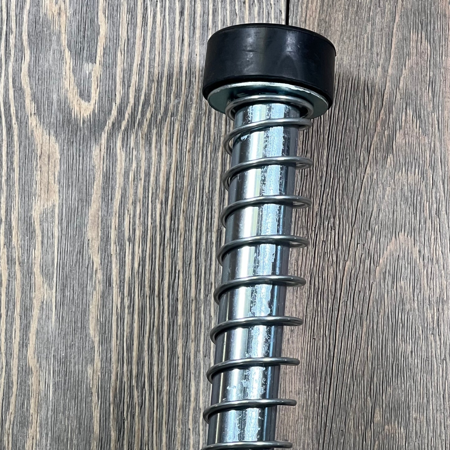 Garage door plunger spring with rubber bumper, 15-inch, ideal for left or right garage door opener systems.