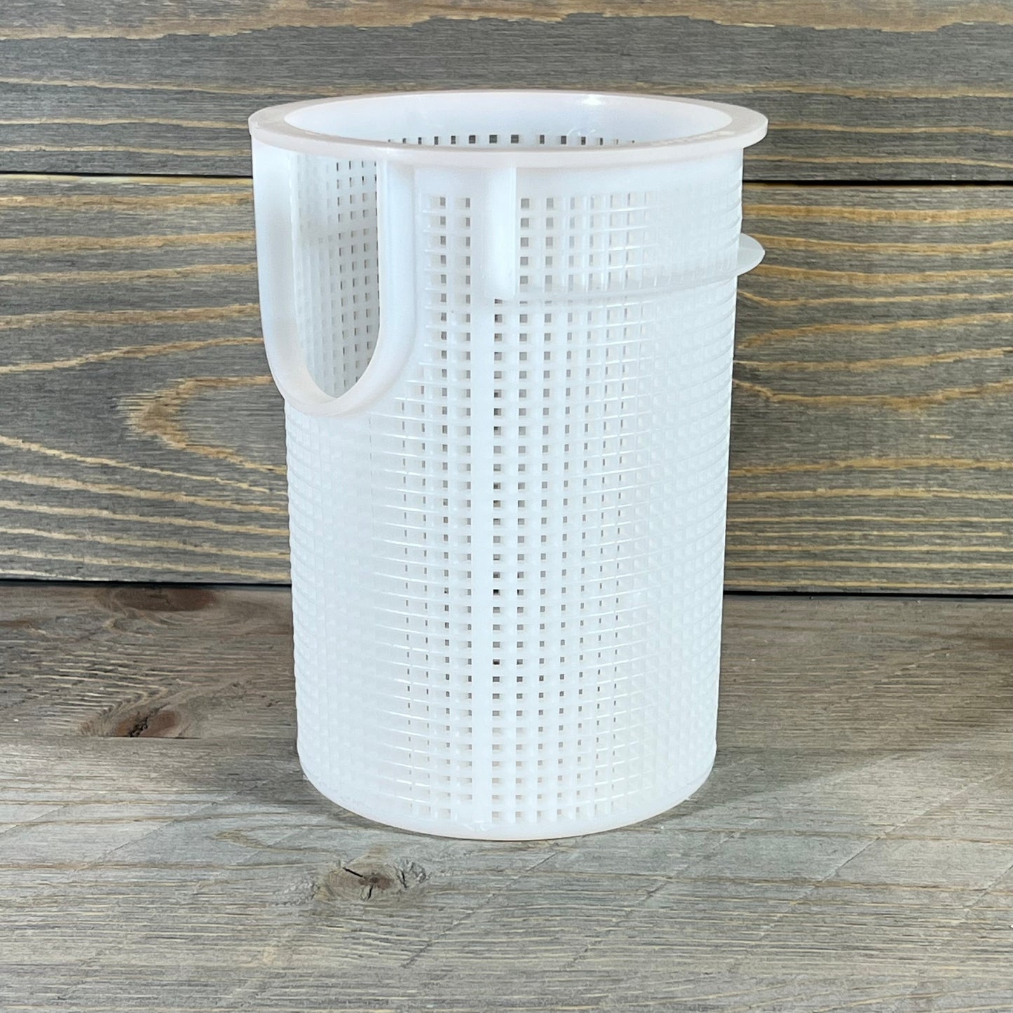Durable white plastic strainer basket for Pentair Sta-Rite suction trap assembly on a wooden surface.