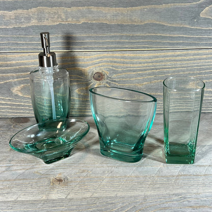 Elegant green teal glass bathroom accessory set with five unique pieces on a rustic wood background.