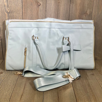 Stylish blue convertible garment bag with shoulder strap on wooden floor, perfect for travel and organization.