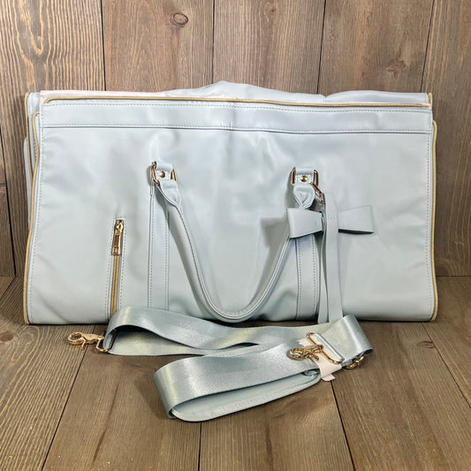 Stylish blue convertible garment bag with shoulder strap on wooden floor, perfect for travel and organization.