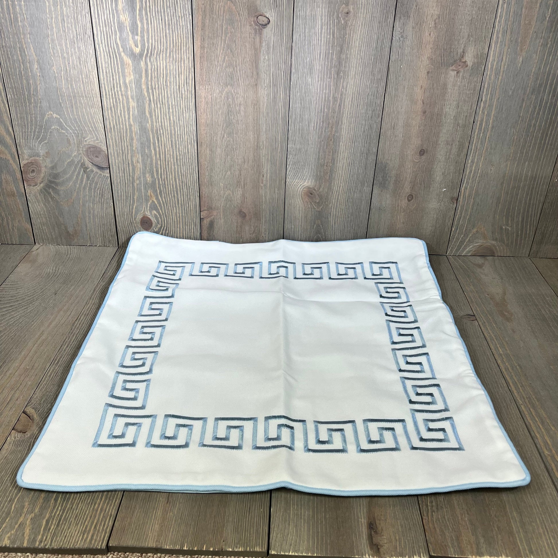 Baby blue embroidered Greek key pillow cover on wooden surface, showcasing premium quality and water-repellent fabric.