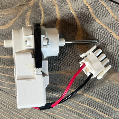 Evaporator fan motor for Frigidaire, Kenmore refrigerators, model 5304514392, shown on wooden surface.