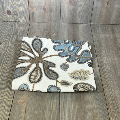 Jacquard tropical leaf pattern throw pillow cover in blue and cream, folded on a wooden surface, 20x20 inches.