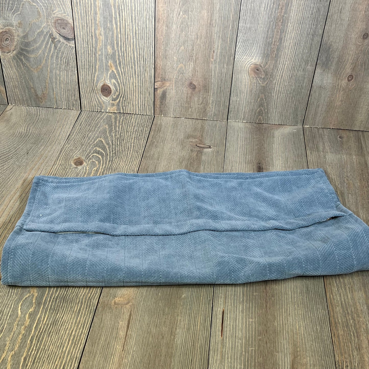 Dusty blue chenille pillow cover folded on rustic wood background, showcasing elegant texture and farmhouse style.