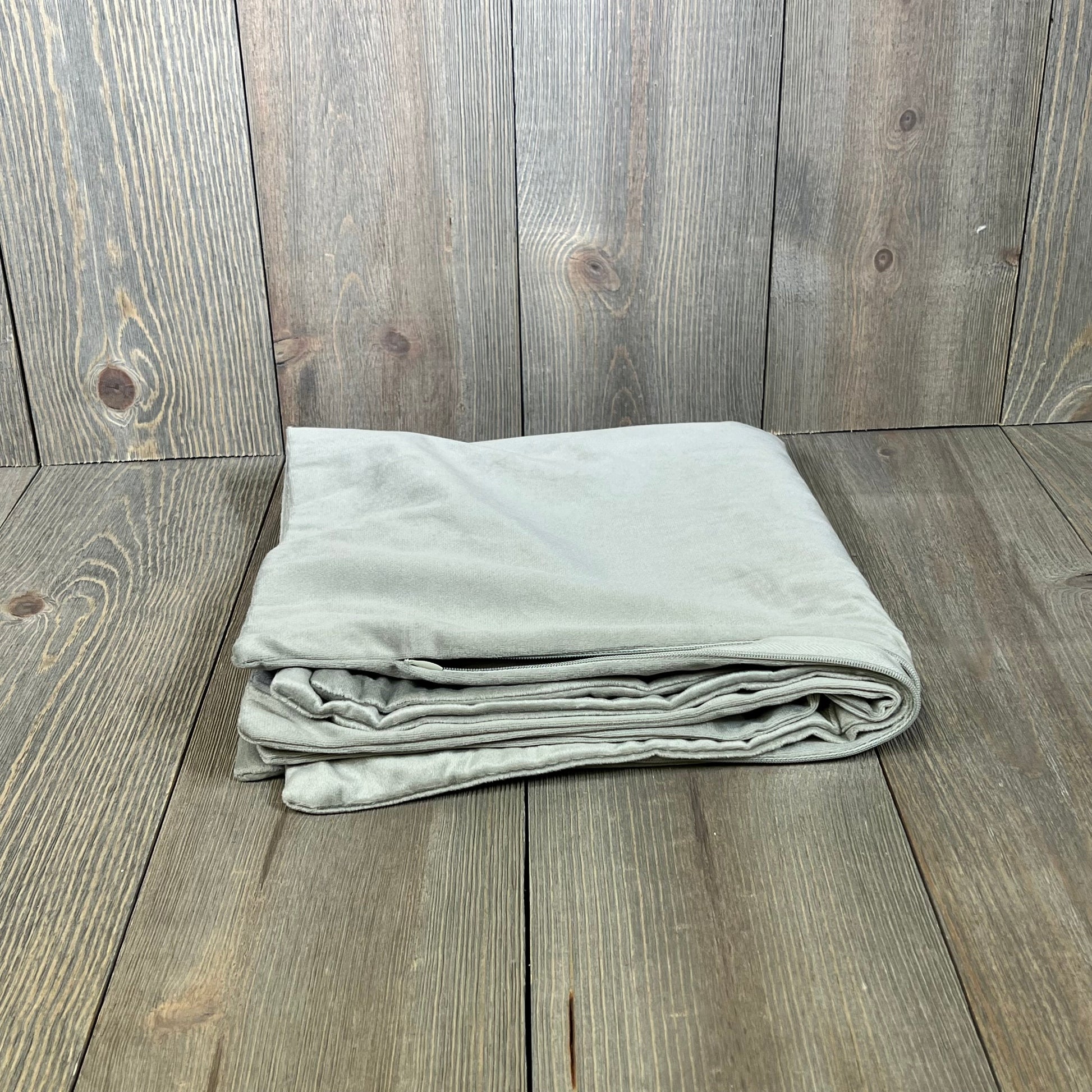 Light-grey velvet pillow covers folded on wooden floor, showcasing soft texture for farmhouse decor, 22x22 inch size.