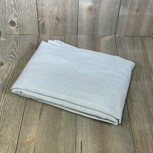 Folded grey linen textured tablecloth, 60 x 104 inches, on rustic wooden surface; premium, wrinkle-free, spill-proof fabric.