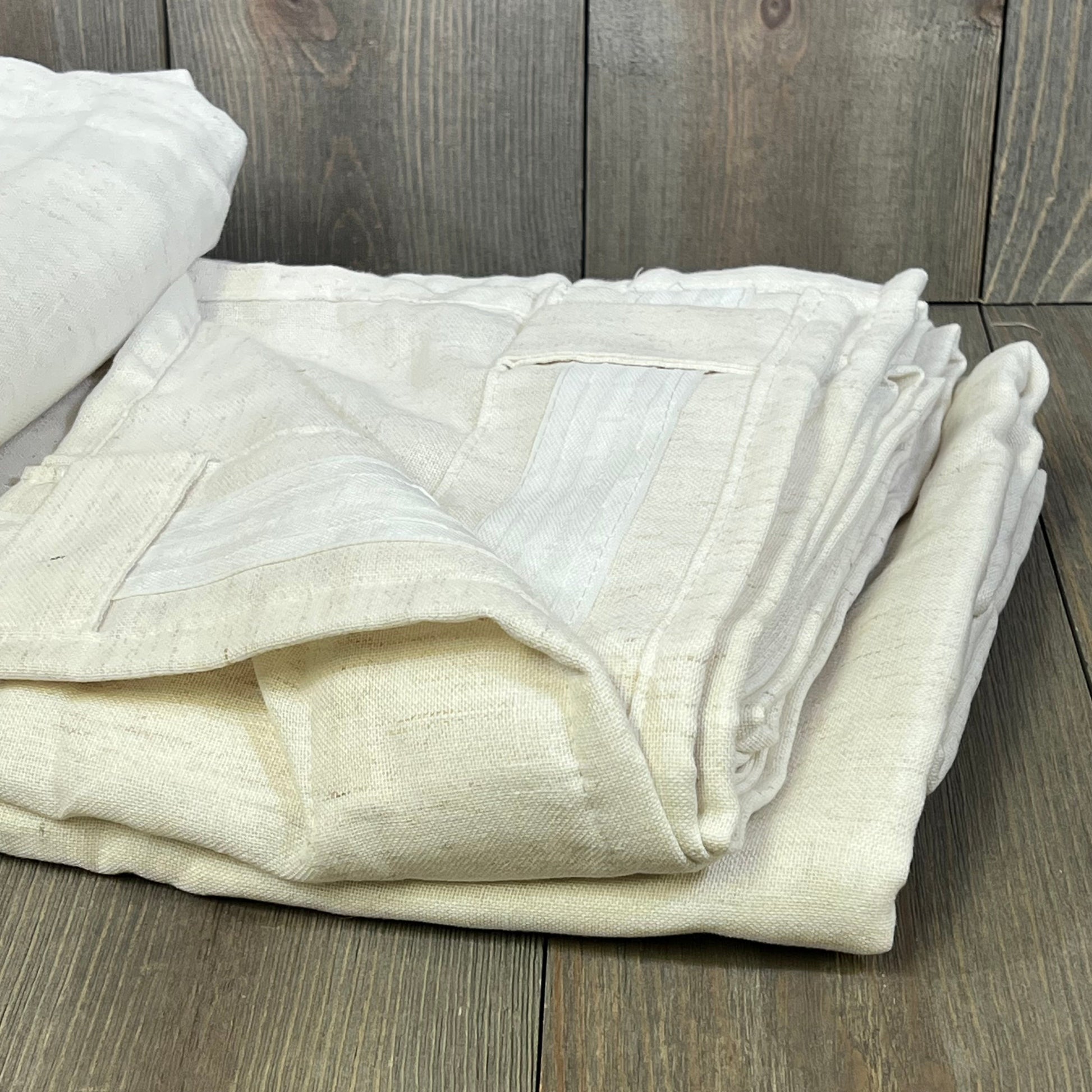 Cream linen curtains folded neatly, showcasing pleated back tab design, ideal for wide windows and sliding doors.