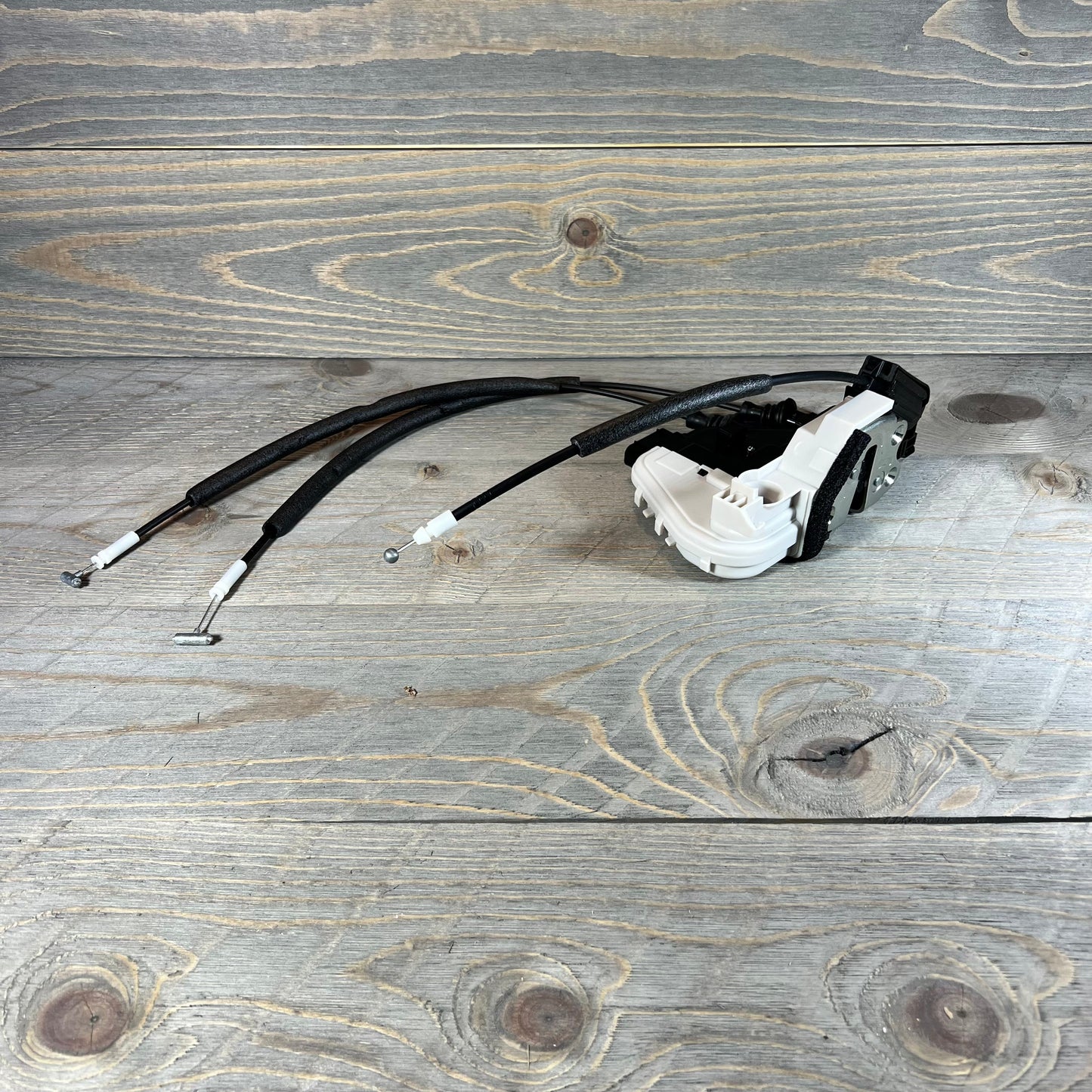 Front right door lock actuator for 2013-2019 Hyundai Santa Fe, replacement part with cables on wooden background.