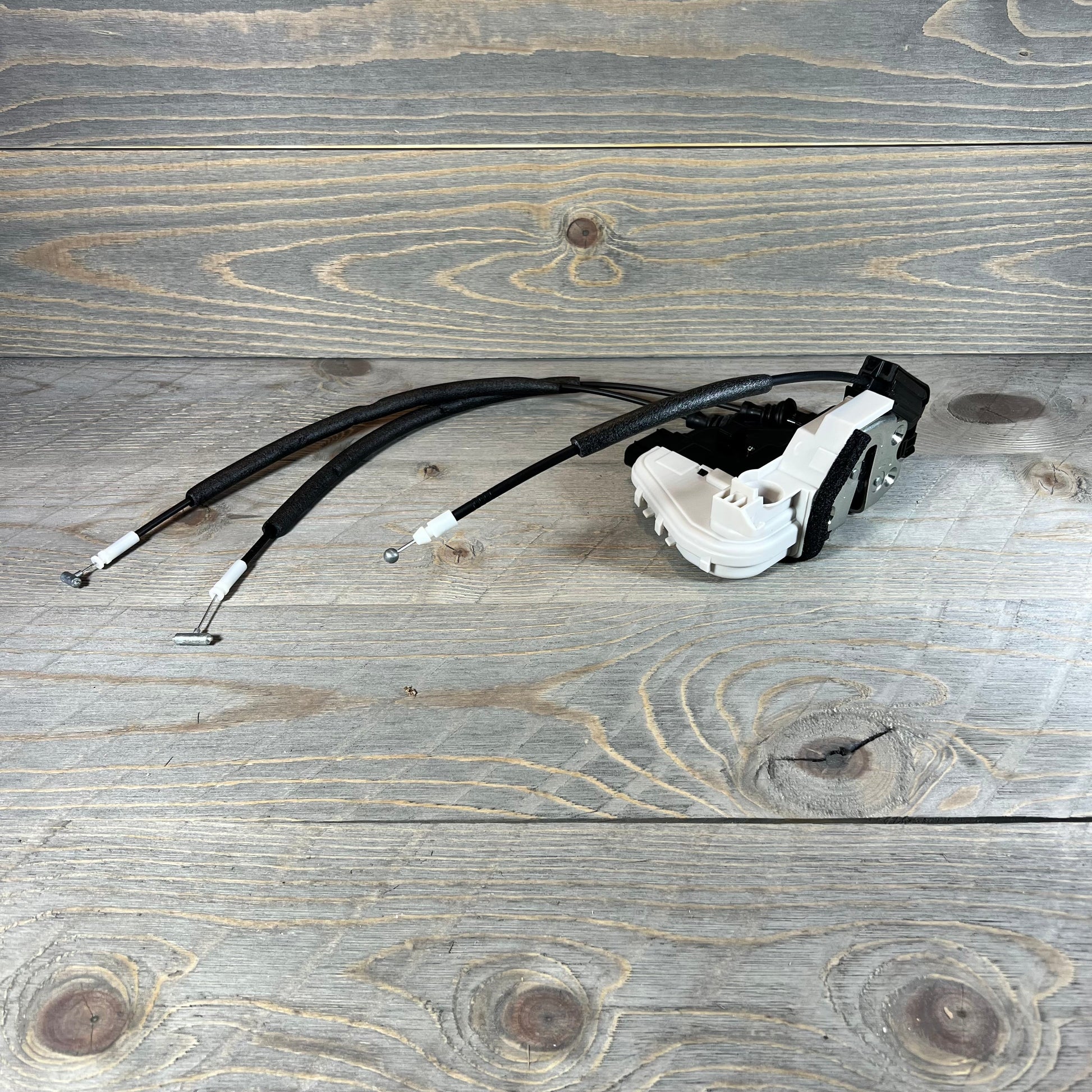 Front right door lock actuator for 2013-2019 Hyundai Santa Fe, replacement part with cables on wooden background.