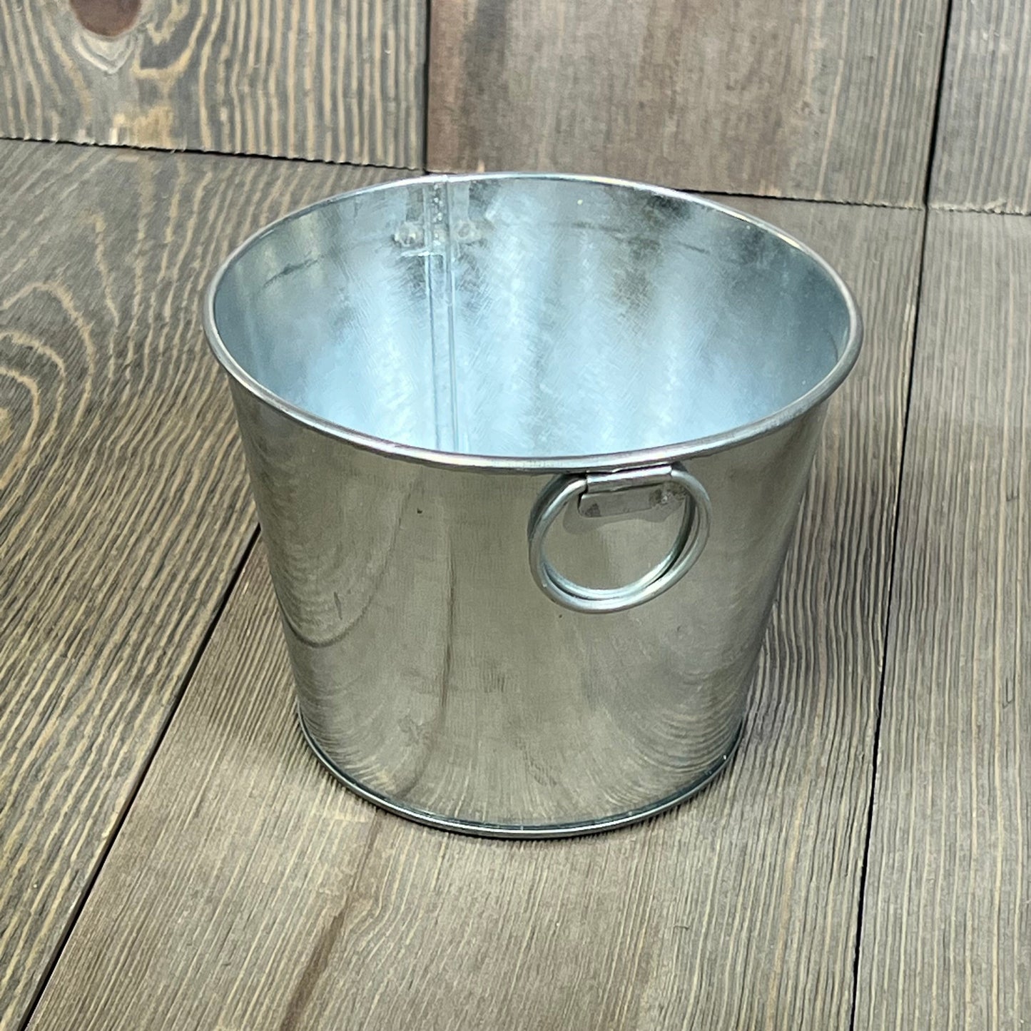 Mini galvanized bucket with handle on wooden surface, ideal for crafts or decor, size 4.5 x 3.5 inches.